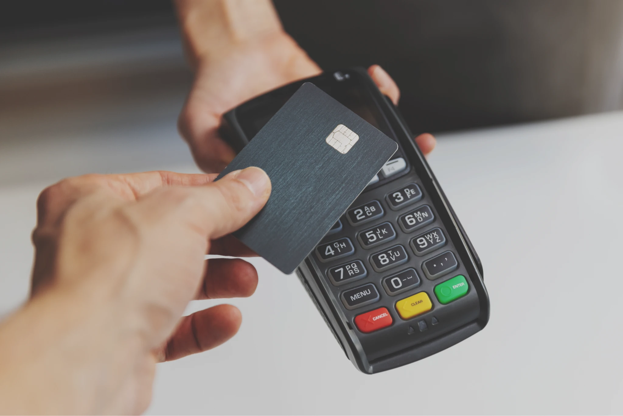 A close-up image of a POS payment process system, with a credit card being held up against a phone