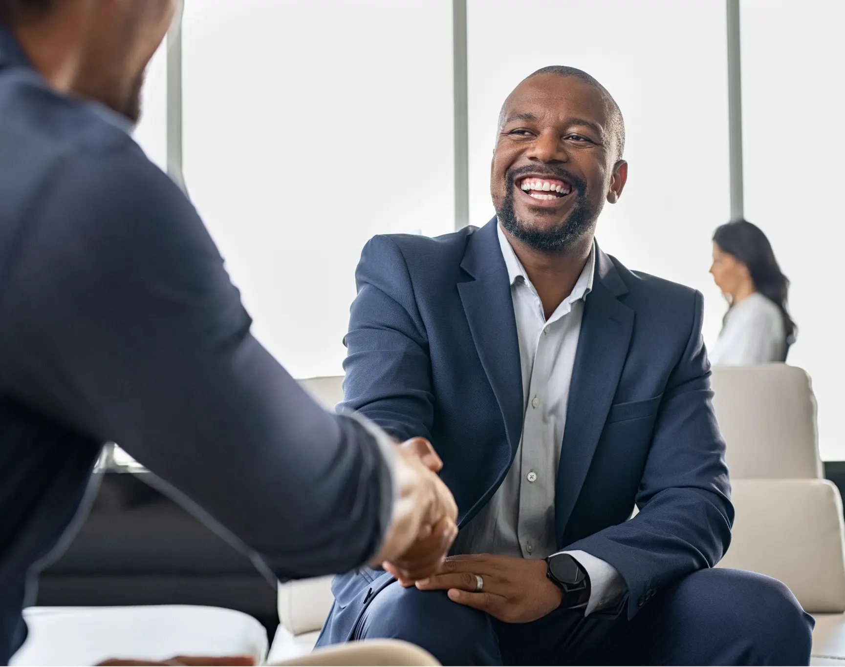 Two businessmen in suits sitting in an office lobby, shaking hands