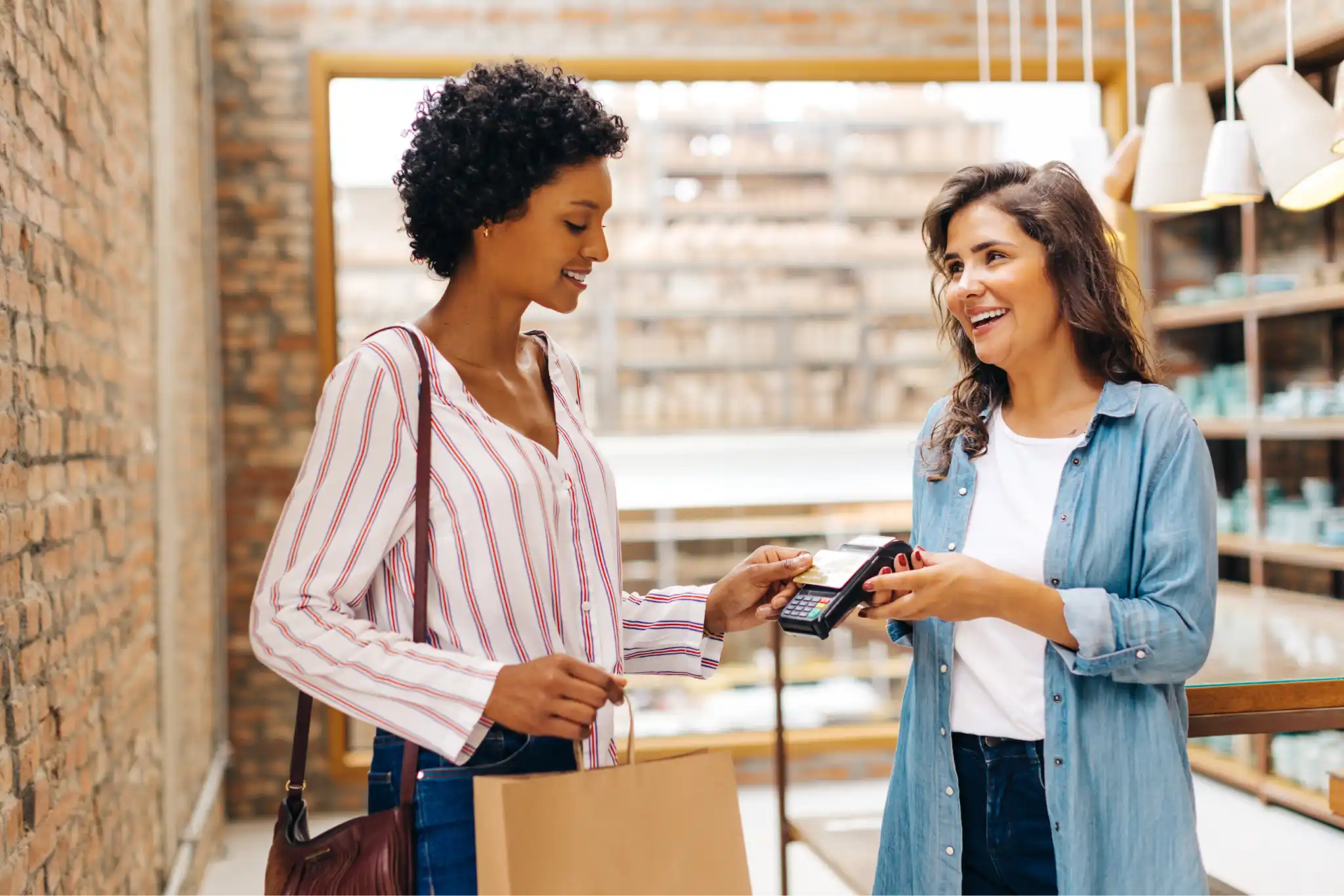 A woman placing her credit card against a mobile POS system held by an employee